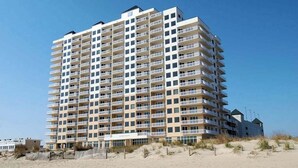 Een meerlaags hotel met balkons, nabij een strand.