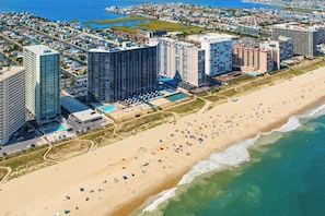 A coastal hotel with multiple high-rise buildings, a beach, and a pool area. - Adorable beachfront condo with balcony, incredible views, pools & game room (Ocean City)