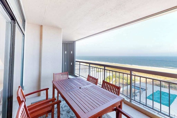 Un balcon avec une table et des chaises, donnant sur l’océan.