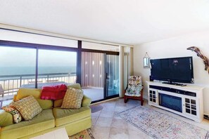 Un salon avec un canapé, un téléviseur et une vue sur l’océan.