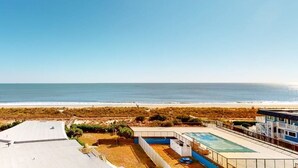 Une propriété résidentielle dotée d’une piscine, d’un patio couvert et offrant une vue sur la plage.