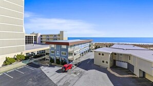 Un hotel con parcheggio, un'auto rossa e vista sull'oceano.