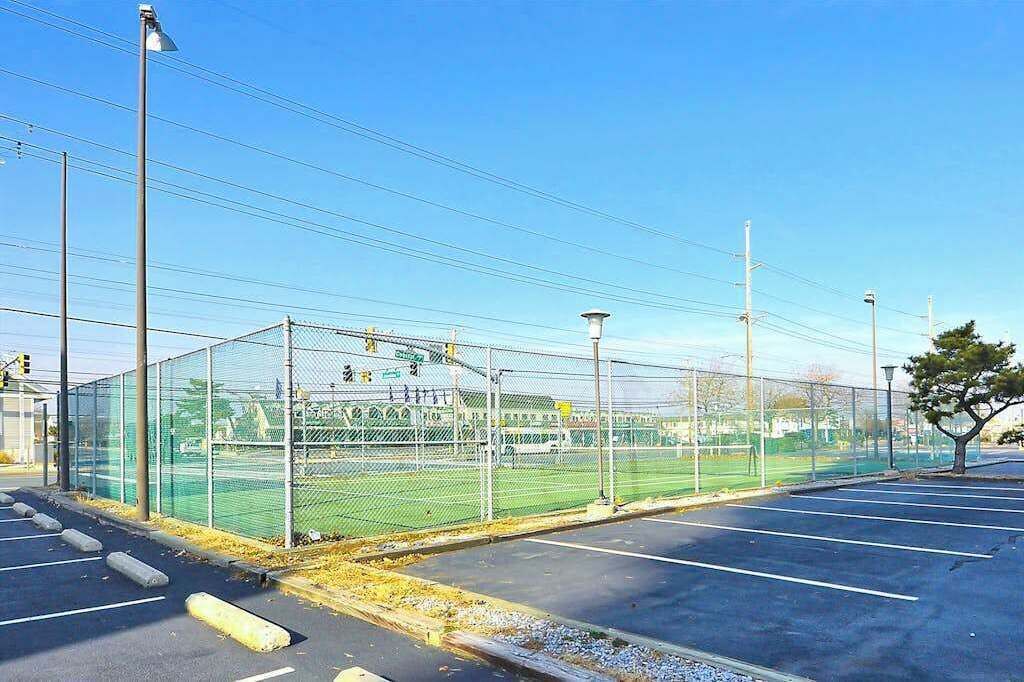 A fenced sports field with a parking lot in the foreground.