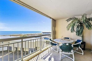 Ein Balkon mit Meerblick, einem Tisch mit Stühlen und einer Kübelpalme.