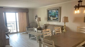 Ein Wohnzimmer mit Esstisch, Stühlen, einer Couch, einer Lampe und einem Gemälde.
