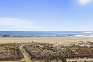 A beach with a sandy path leading to the water, a wooden fence, and a clear sky. - Attractive Suite in Oceanfront Complex w/Free WiFi, Private Washer/Dryer, & AC (Ocean City)