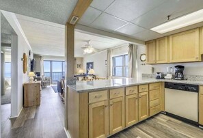 A spacious kitchen with wooden cabinets, a granite countertop, and a dishwasher. - Attractive Suite in Oceanfront Complex w/Free WiFi, Private Washer/Dryer, & AC (Ocean City)