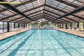 A covered swimming pool with lounge chairs and a clear view of the surrounding area. - Beachfront condo with indoor pool, new fitness center, ocean & beach views (Ocean City)