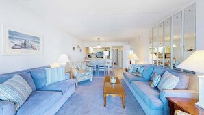 A living room with a sofa set, a coffee table, and a dining area in the background. - Excalibur 303 (Ocean City)