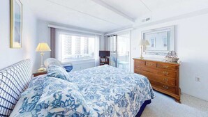 A bedroom with a bed, dresser, and a window with curtains. - Excalibur 303 (Ocean City)