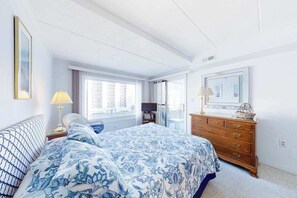 Ein Schlafzimmer mit Bett, Kommode und einem Vorhangfenster.