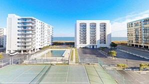 A modern building with multiple balconies, a tennis court, and a view of the sea. - Excalibur 303 (Ocean City)
