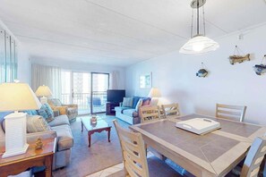 Ein modernes Wohnzimmer mit einer Couch, einem Fernseher, einem Esstisch und Stühlen.