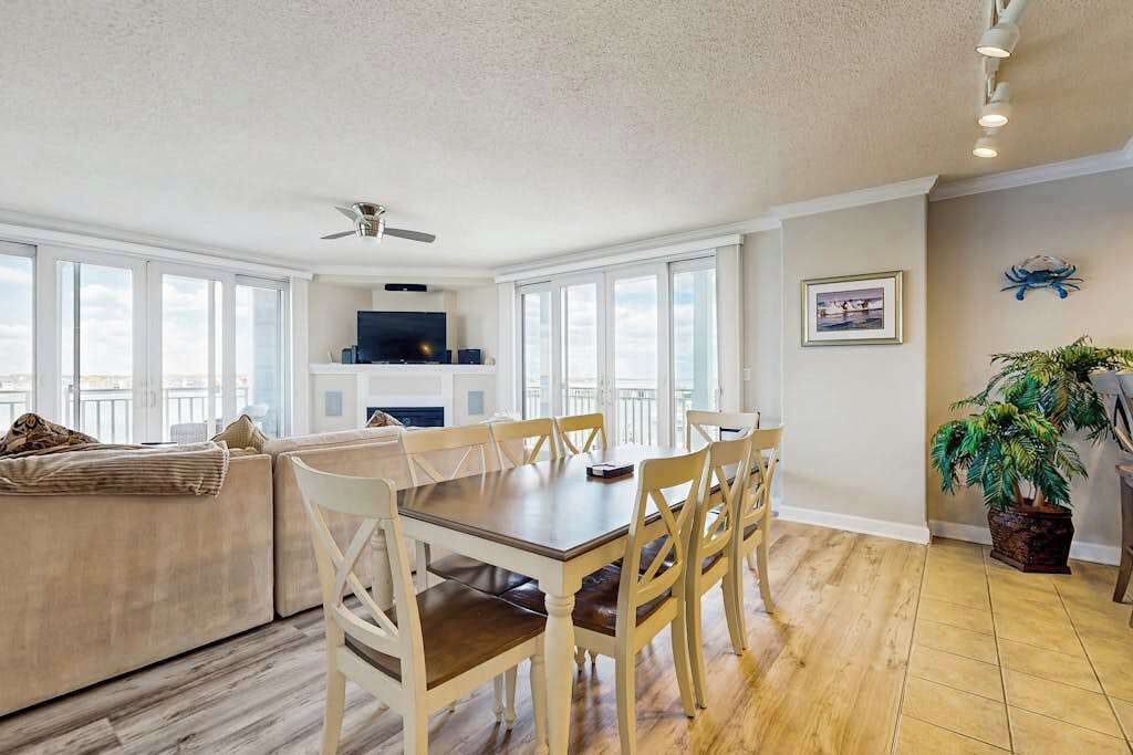 A spacious living area with a dining table, chairs, a sofa, and a ceiling fan.