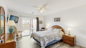A bedroom with a bed, bedside tables, a TV, a chair, and a balcony. - Club Ocean Villa II 144 (Ocean City)