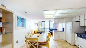 A compact kitchen with white cabinets, a dining table with chairs, and a large window offering a view. - Beautiful Home in Oceanfront Building w/Shared Pool, Free WiFi, Central AC (Ocean City)