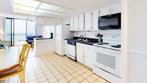 A compact kitchen with white cabinets, a stove, and a microwave. - Beautiful Home in Oceanfront Building w/Shared Pool, Free WiFi, Central AC (Ocean City)