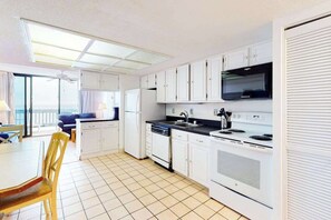 A compact kitchen with white cabinets, a stove, and a microwave. - Beautiful Home in Oceanfront Building w/Shared Pool, Free WiFi, Central AC (Ocean City)