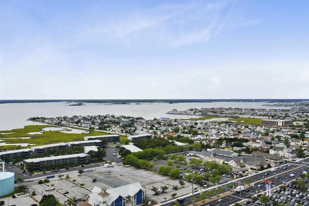 Un paysage urbain côtier avec des immeubles résidentiels, une vaste étendue d’eau et un imposant bâtiment bleu.