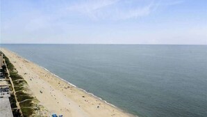 A beach with a long stretch of sand, a clear sky, and a calm sea. - Beautiful Home in Oceanfront Building w/Shared Pool, Free WiFi, Central AC (Ocean City)