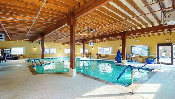 En inomhuspool med träbjälkar, ett betonggolv och en gul vägg.