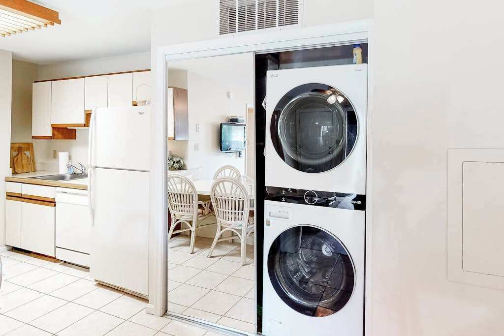 A compact kitchen with white cabinets, a refrigerator, and a washing machine.