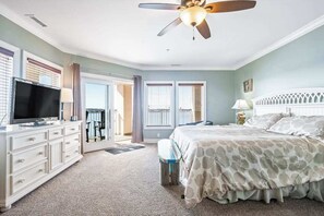 Ein Schlafzimmer mit einem Bett, einem Schminktisch, einem Fernseher und einem Deckenventilator.
