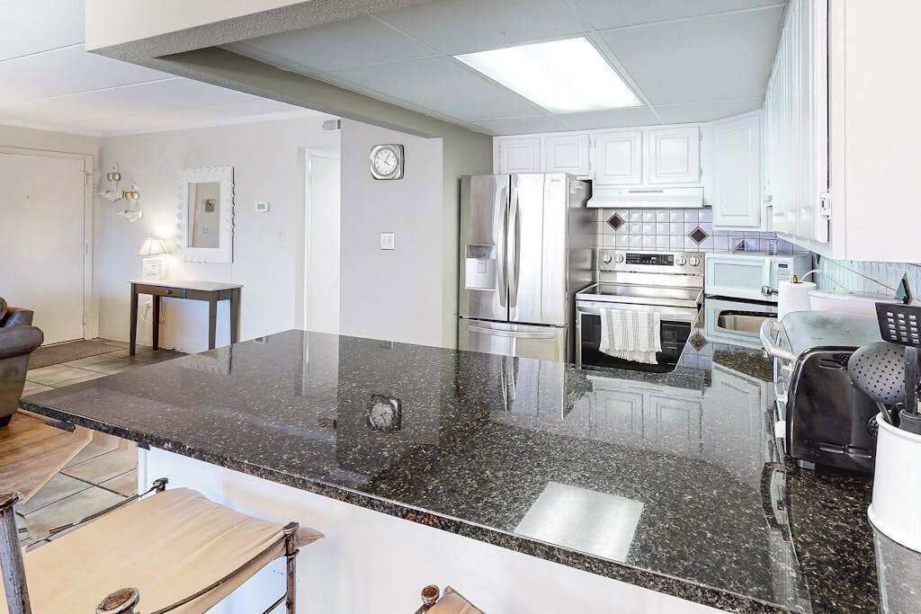 Una cocina moderna con encimera de granito, electrodomésticos de acero inoxidable y armarios blancos.