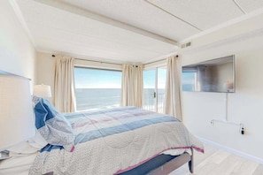 Une chambre d’hôtel avec un lit, un téléviseur fixé au mur et une fenêtre avec des rideaux.