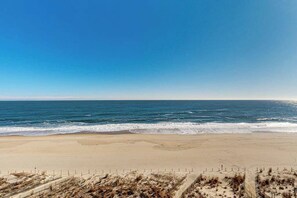 Une plage avec une clôture au premier plan et un ciel dégagé.