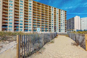 Un hôtel à plusieurs étages doté d’une cour intérieure, d’un sentier sablonneux et d’une clôture en bois.