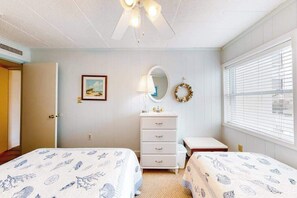 A bedroom with two beds, a dresser, a mirror, a wall decoration, and a window with blinds. - Top-floor, oceanfront condo w/ gorgeous view, balcony, beach access, & WiFi (Ocean City)