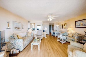 A spacious living area with a ceiling fan, a dining table, and multiple seating arrangements. - Top-floor, oceanfront condo w/ gorgeous view, balcony, beach access, & WiFi (Ocean City)