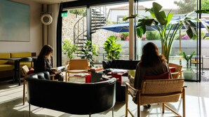 Un intérieur moderne avec un escalier, un coin salon et de grandes fenêtres.