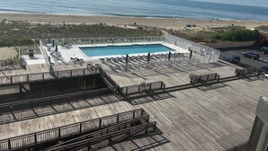 Piscina no terraço com vista para o oceano, rodeada por um deck de madeira e espreguiçadeiras.