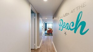 Um corredor com uma placa na parede que diz 'A vida é melhor na praia' e uma área de refeições ao fundo.