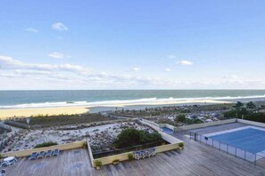 Blick auf einen Strand vom Dach eines Gebäudes mit Pool und Liegestühlen.