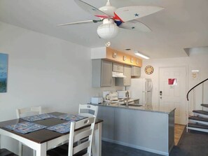 Eine moderne Küche mit weißen Schränken, einer zentralen Kochinsel und einem Deckenventilator mit Sternenmuster.