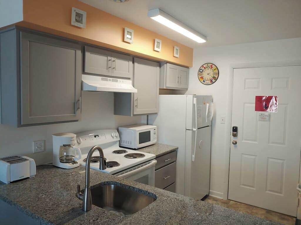 Cozinha compacta com pia, fogão, micro-ondas e geladeira.