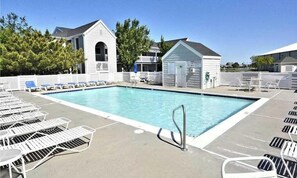 Ein Swimmingpool mit Liegestühlen, eine kleine Gartenhütte und ein weißes Gebäude mit Veranda.