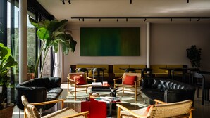 Un espace de détente moderne avec des canapés en cuir, des fauteuils en osier et un grand tableau abstrait accroché au mur.