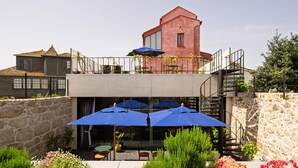Un bâtiment à la façade rouge, doté d’un balcon orné de parasols bleus et d’un escalier menant à un étage supérieur.