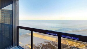Un balcón con vistas a la playa y al océano, un letrero que indica acceso restringido y un cielo despejado.