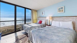 A hotel room with two beds, a large window with a view of the beach, and a painting on the wall. - Classic, alluring beachfront condo with balcony, views, pools, gym & tennis (Ocean City)