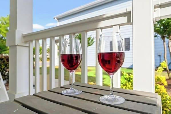 Two wine glasses on a wooden table with a white railing in the background. - Gulf Stream Cottages 1928-walk to beach (Myrtle Beach)