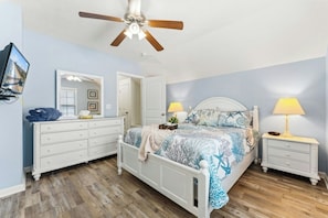 A bedroom with a bed, two bedside tables, a dresser, a ceiling fan, and a mirror. - Gulf Stream Cottages 1928-walk to beach (Myrtle Beach)