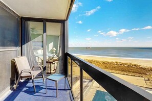 Ein Balkon mit Blick auf den Strand, inklusive Tisch und zwei Stühlen.