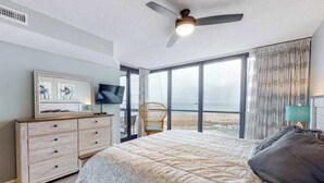 Ein Schlafzimmer mit Bett, Schminktisch, Fernseher, Sessel und Meerblick.