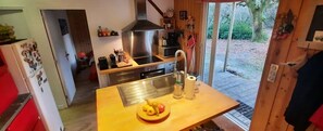 Una cocina compacta con extractor de acero inoxidable, un lavamanos y una encimera de madera.