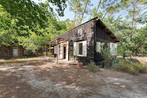 A rustic wooden cabin with a porch, surrounded by trees. - Holiday Home "Cabane Eden Pyla" with Private Terrace and Garden (La Teste-de-Buch)